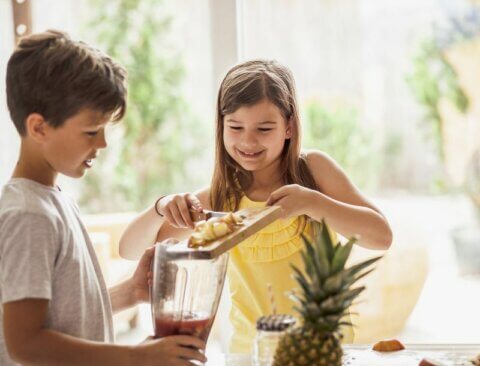 Zwei Kinder bereiten etwas sommerliches zum Essen vor.