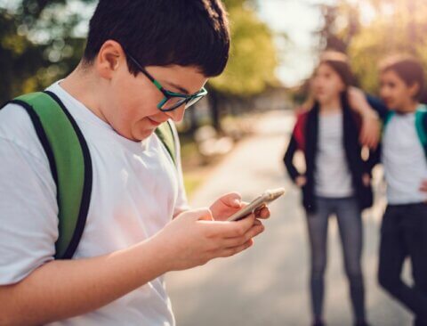 Man sieht einen Jungen, der leicht grinsend auf sein Smartphone starrt.